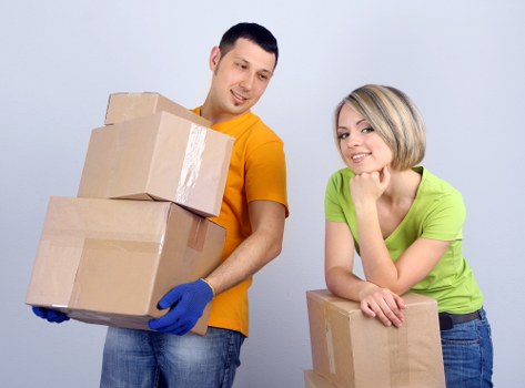 Removalists carrying packed boxes and protecting furniture